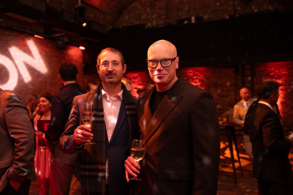Martin raising a toast at a business event, holding a champagne glass, with a crowd of attendees in the background