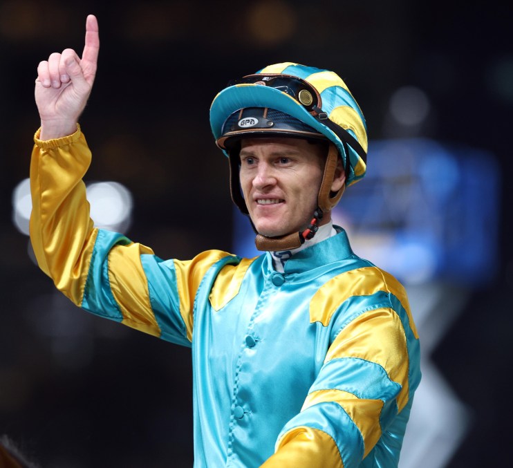 Jockey Zac Purton wearing racing attire on a race track, showcasing determination and focus during a competitive horse rac...