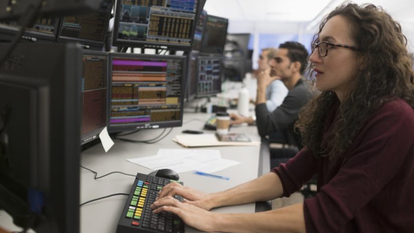 Bloomberg trading terminal with live market data and charts, trader analyzing statistics for strategic decision-making