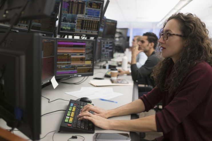 Bloomberg trading terminal with live market data and charts, trader analyzing statistics for strategic decision-making