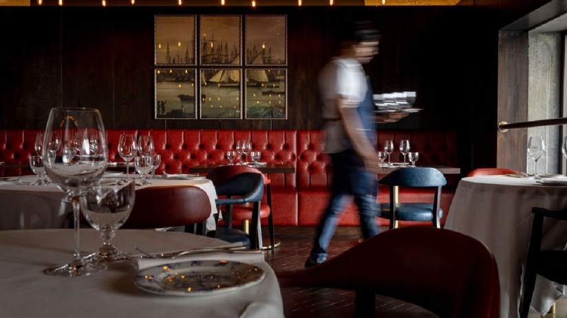 Chop house interior with rustic decor, featuring wooden tables, ambient lighting, and patrons enjoying meals.