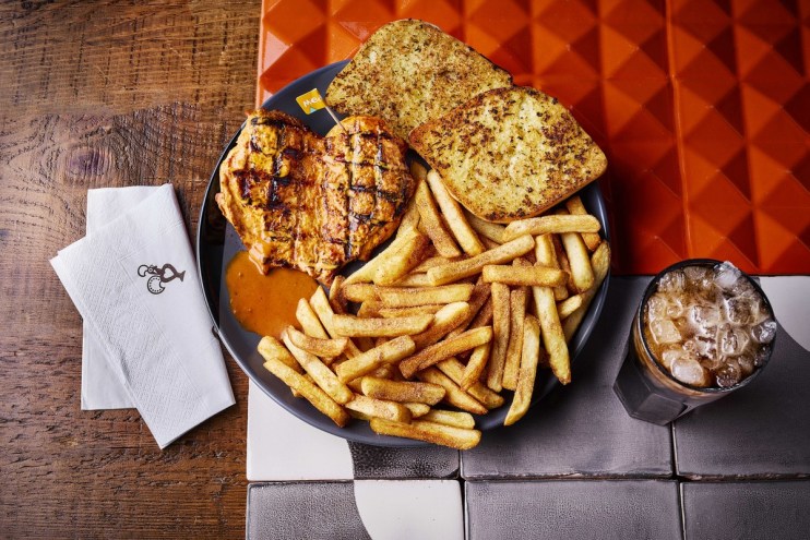 Nandos Chicken Butterfly with PERi-salted chips, garlic bread, and a bottomless Coke Zero on a restaurant table