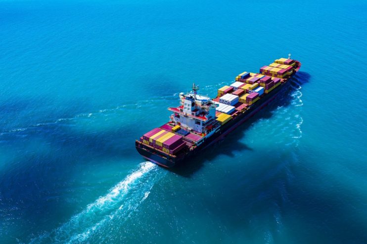 Cargo ship navigating a busy port, showcasing global trade and shipping industry operations in a bustling maritime setting