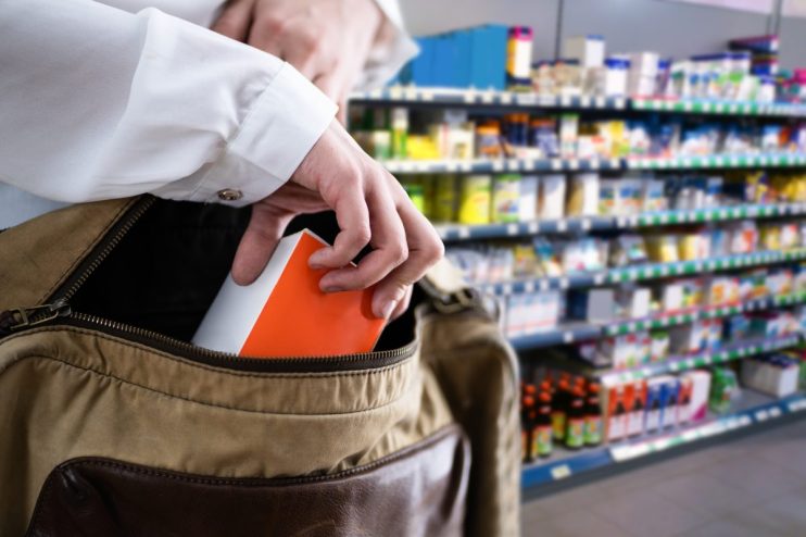 Shoplifting incident in retail store with security camera footage showing suspect concealing merchandise in jacket