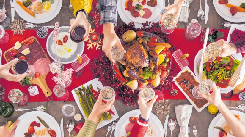 Festive Christmas lunch table with roasted turkey, seasonal vegetables, and holiday decorations, evoking a warm holiday ga...