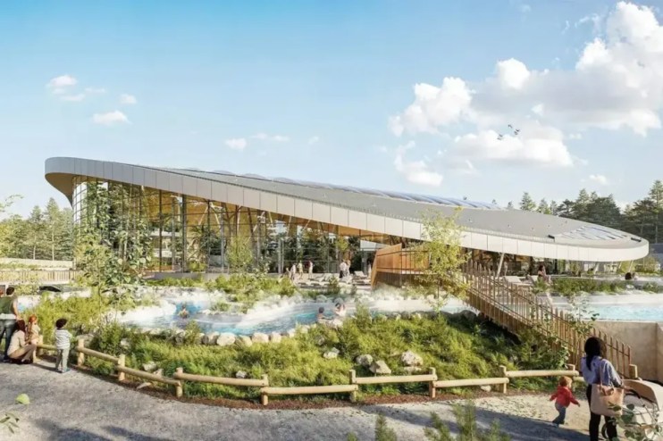 Center Parcs resort aerial view with lush greenery, accommodations, and recreational facilities under clear blue skies