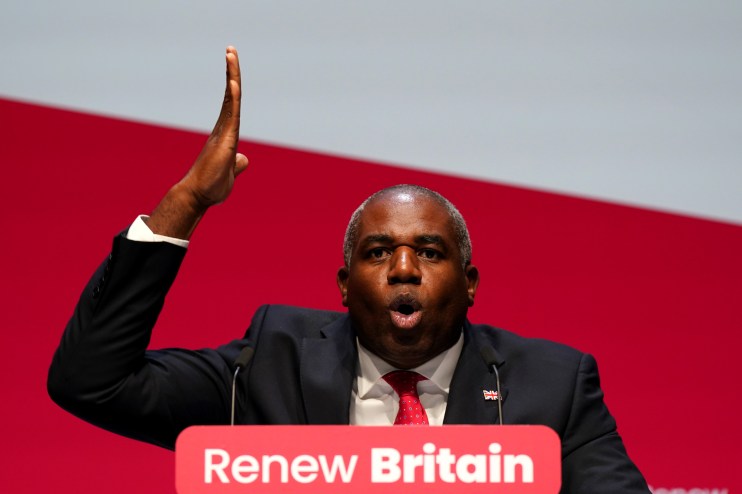 David Lammy speaking at a press conference with a focused expression, wearing a suit and tie, addressing key issues.
