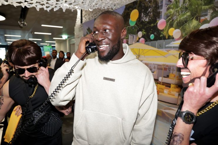 Stormzy attends ICAP Charity Day event, engaging with attendees at a business-focused philanthropic gathering.