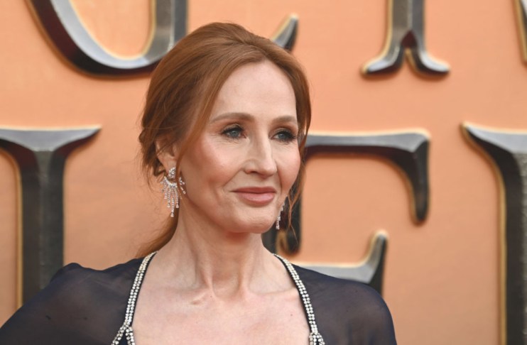 JK Rowling speaking at a public event, wearing a formal outfit, addressing an audience with a focused expression.