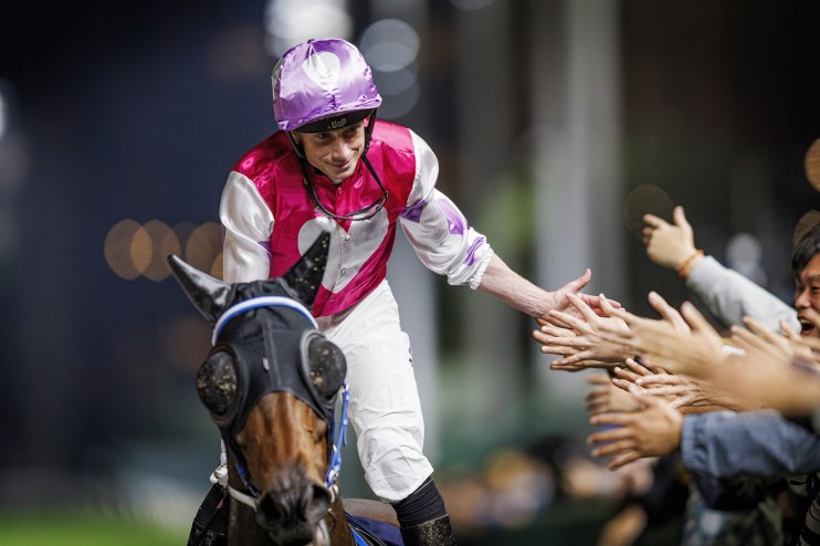 Ryan Moore celebrating victory at Happy Valley Racecourse with a jubilant expression, showcasing his racing triumph.