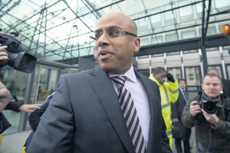 Sanjeev Gupta speaking at a business conference, wearing a suit, addressing sustainability in the steel industry.