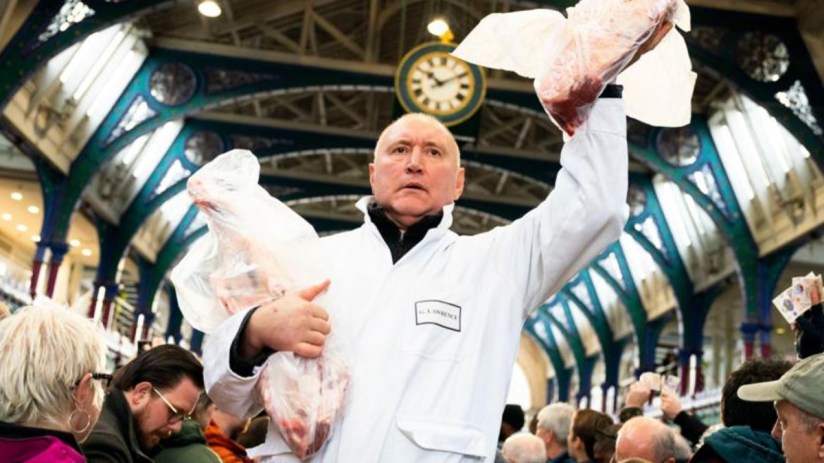 Smithfield meat market auction with bustling crowd, showcasing various meat cuts and enthusiastic bidders in a lively setting