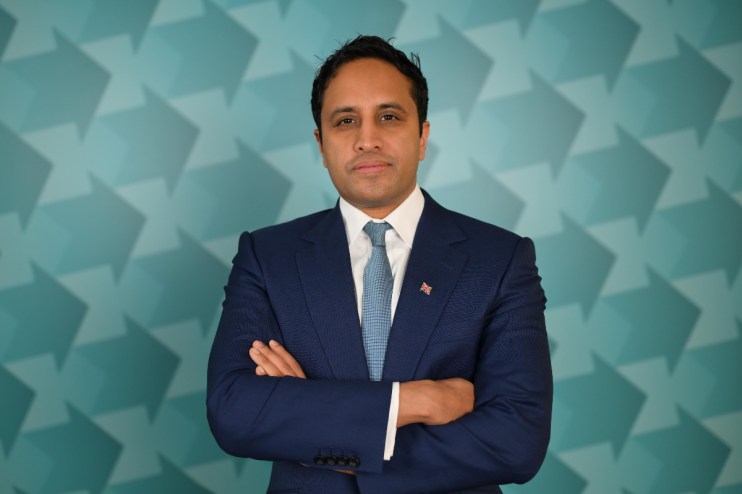 Zia Yusuf at a business event, wearing a suit and tie, delivering a keynote speech in a modern conference setting