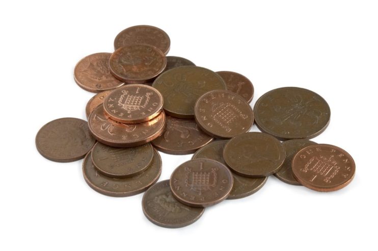 Various coins of different denominations stacked and scattered, highlighting economic themes in a business news context.