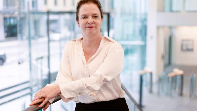 Sara Bailey delivering a speech at a high-profile business conference, engaging an attentive audience with her insights.
