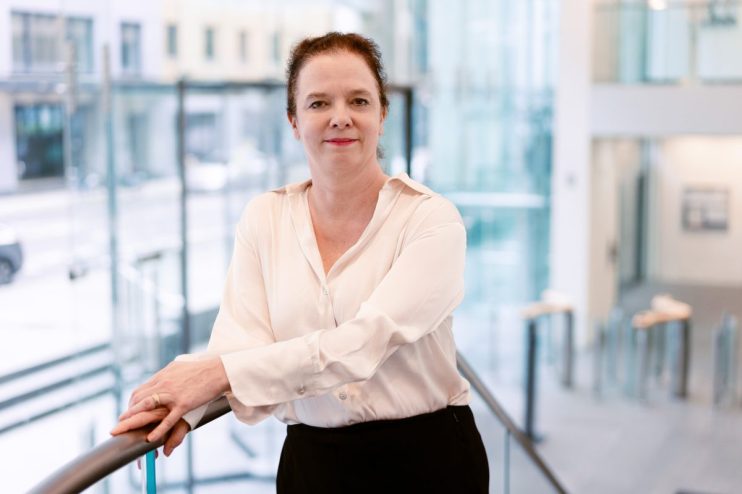 Sara Bailey delivering a speech at a high-profile business conference, engaging an attentive audience with her insights.