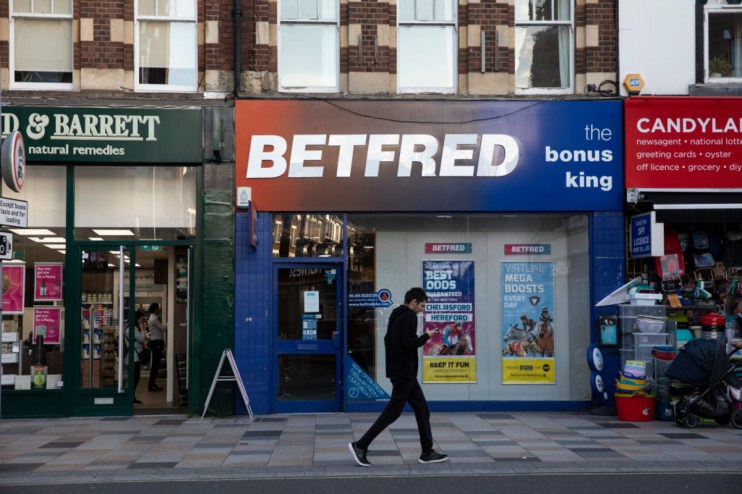 Betfred storefront with prominent signage, displaying current promotions and customers entering and exiting the shop