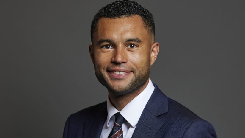 Callum Anderson MP in formal attire standing confidently in front of the parliament building