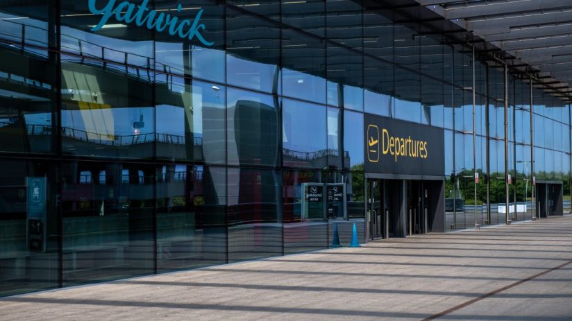 Aerial view of Gatwick Airport showcasing busy terminals and aircraft on runways under clear skies, emphasizing travel act...