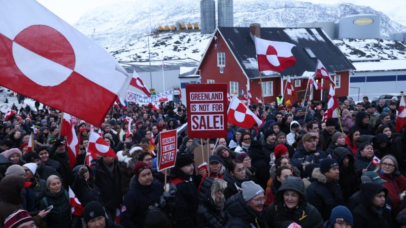 Greenland citizens protest against Trumps territorial threats, holding signs and banners in a public demonstration.