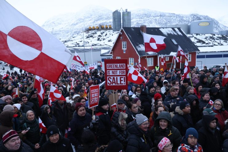 Greenland citizens protest against Trumps territorial threats, holding signs and banners in a public demonstration.