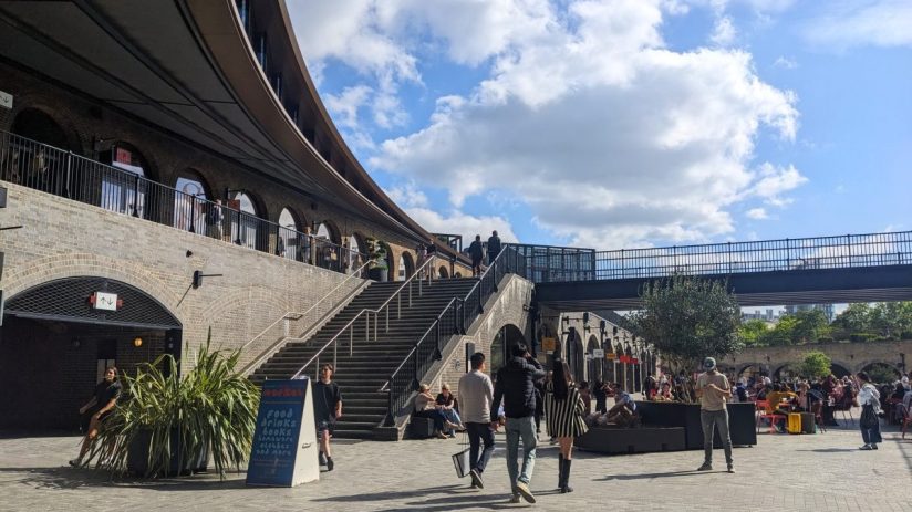 Kings Cross Coal Drops Yard bustling with shoppers and visitors amidst modern architecture and vibrant store displays