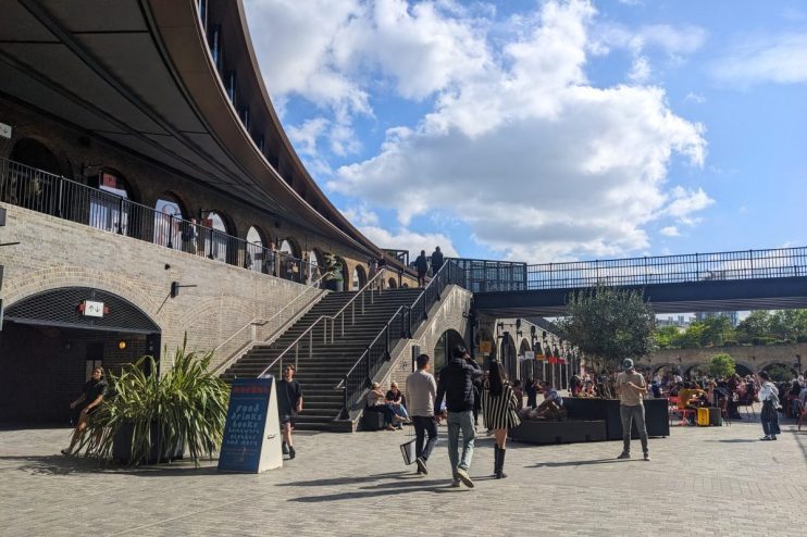 Kings Cross Coal Drops Yard bustling with shoppers and visitors amidst modern architecture and vibrant store displays