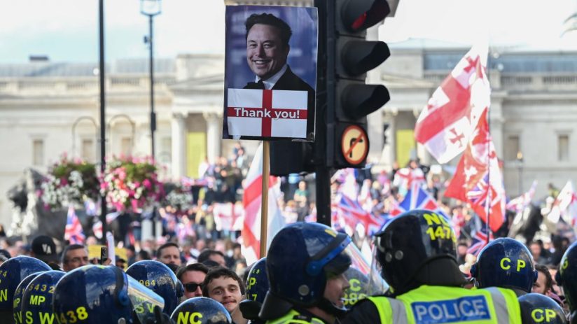 Crowd of protesters holding signs and banners during a public demonstration in a city street, expressing civil unrest.