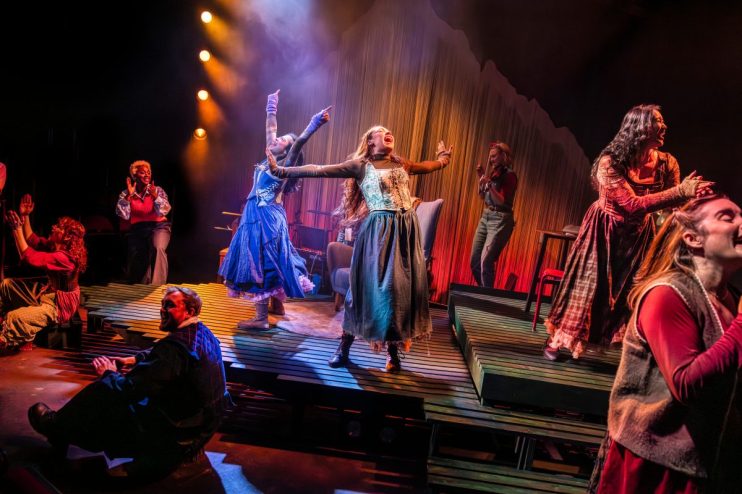 The ensemble of Ballad Lines performing on stage, captured by Pamela Raith, showcasing dynamic expressions and vibrant cos...