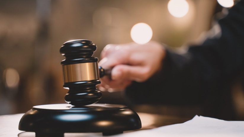 Auction gavel on a wooden block, symbolizing the start of a bidding process in a business setting.