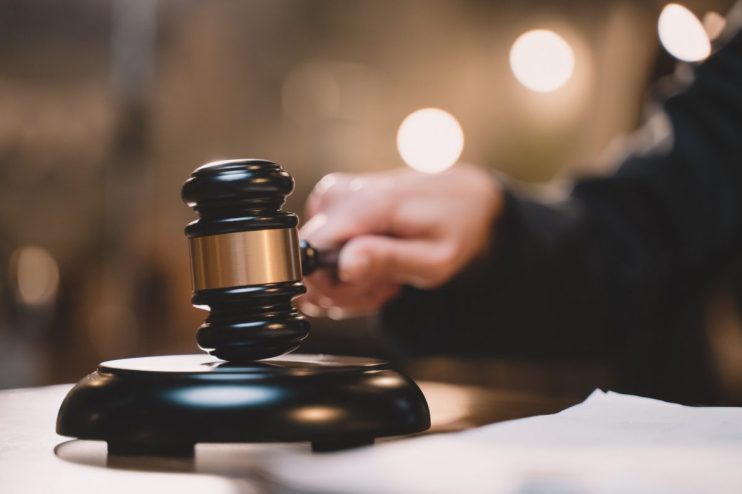 Auction gavel on a wooden block, symbolizing the start of a bidding process in a business setting.