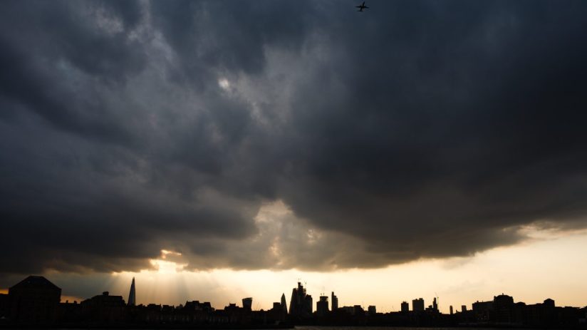 Severe weather impacts business operations with storm clouds looming over a city skyline, highlighting economic challenges.