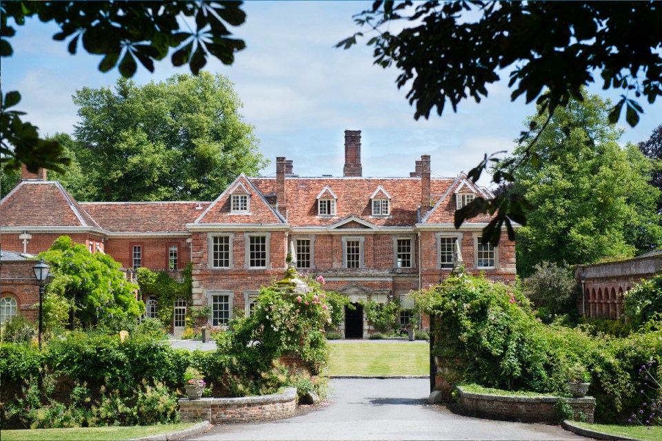Exterior view of Lainston House, showcasing its classic architecture and lush surrounding gardens under a clear sky.