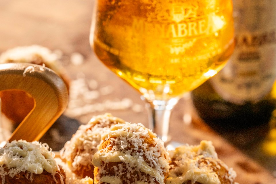 Menabrea beer bottle with label visible, showcasing Italian craftsmanship, set against a rustic wooden background