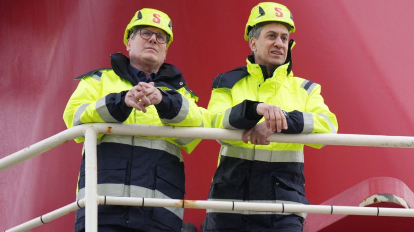 Ed Miliband and Keir Starmer discussing wind energy policy at a press conference, highlighting renewable energy initiatives.