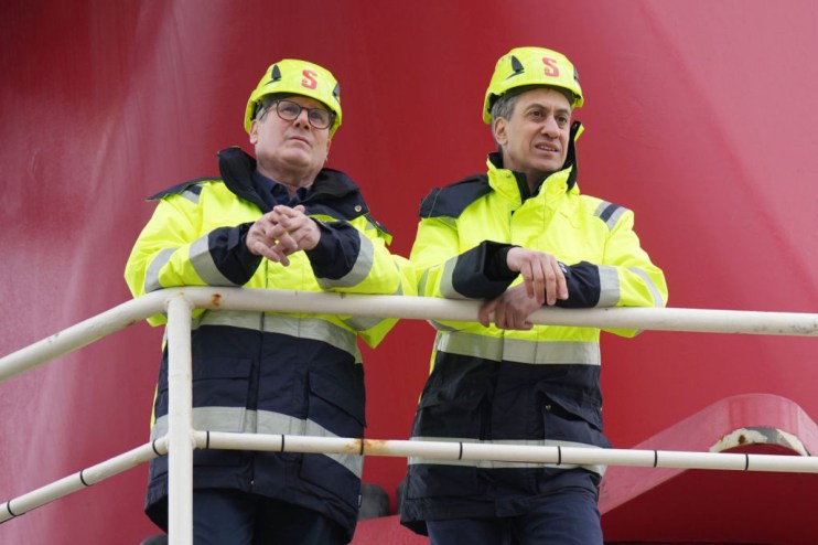 Ed Miliband and Keir Starmer discussing wind energy policy at a press conference, highlighting renewable energy initiatives.