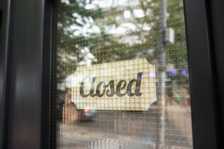 Closed shop with sign on door, reflecting economic impact on local businesses, highlighting shuttered storefront in community