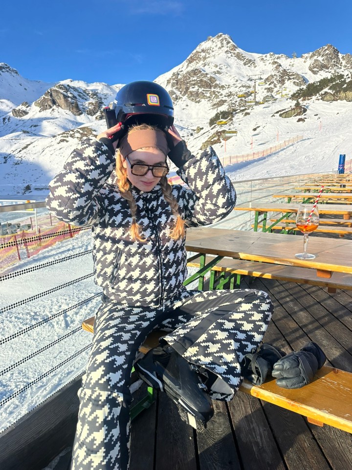 Anna wearing a vibrant ski suit and helmet, confidently skiing down a snowy slope, showcasing winter sports enthusiasm.