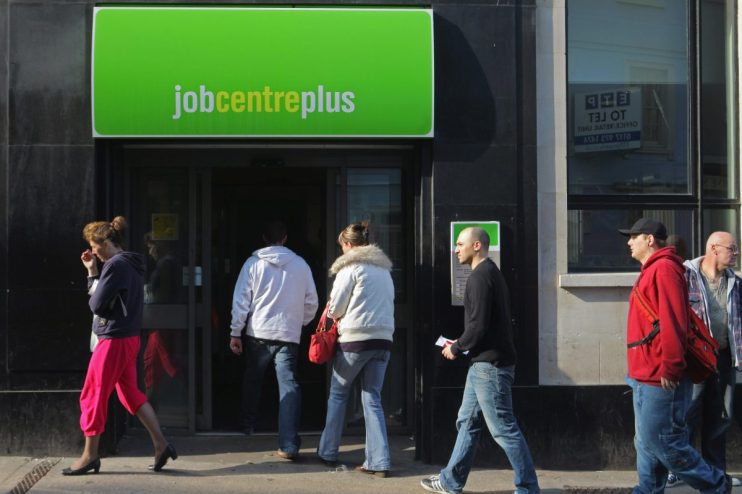 People waiting outside a job centre, highlighting unemployment issues and job search challenges in the current economy.