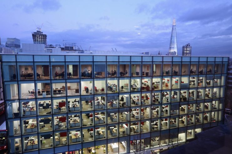 London office workers collaborating on AI and tech projects, surrounded by computers and digital interfaces in a modern wo...