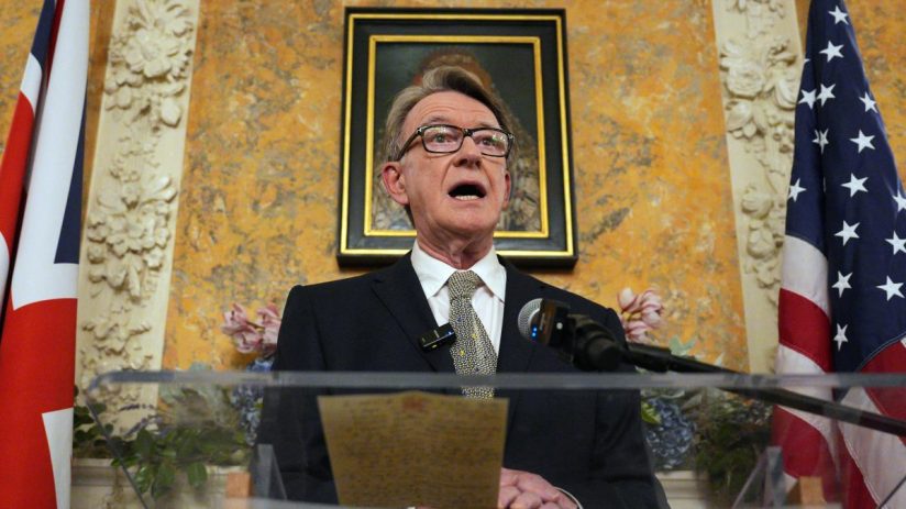 Peter Mandelson speaking at a business conference, wearing a suit and tie, addressing an audience on economic issues