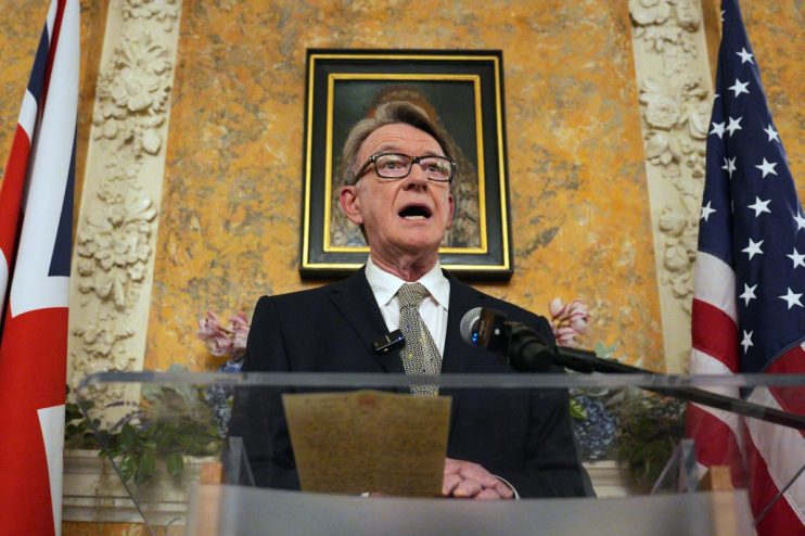 Peter Mandelson speaking at a business conference, wearing a suit and tie, addressing an audience on economic issues