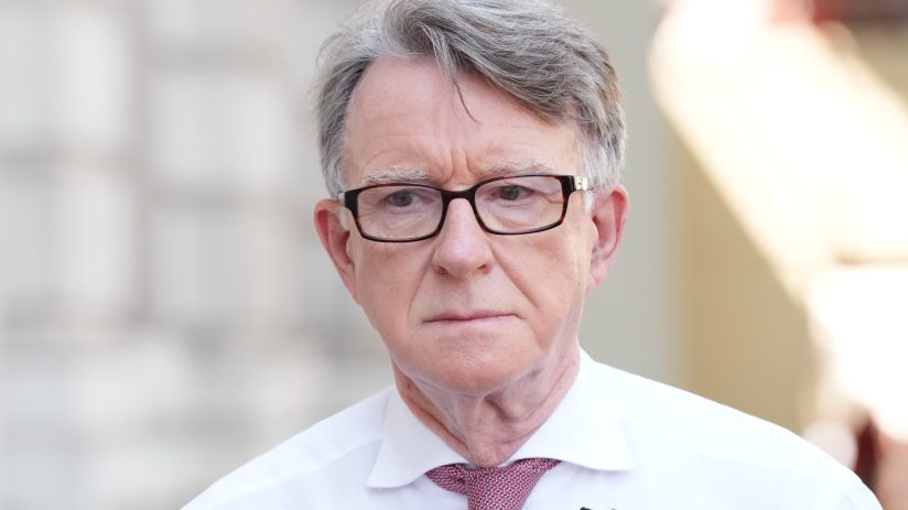 Peter Mandelson speaking at a business conference podium with audience in background, discussing economic strategies.