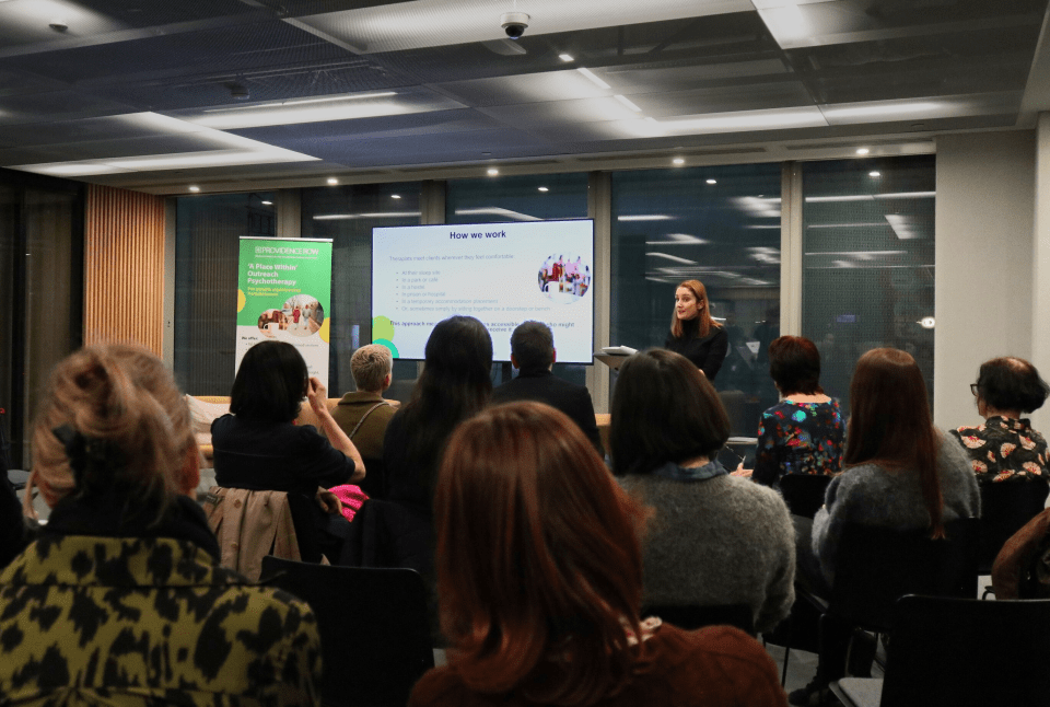 Providence Row Psychotherapy Service Evaluation Report launch event showcasing speakers and attendees in discussion.
