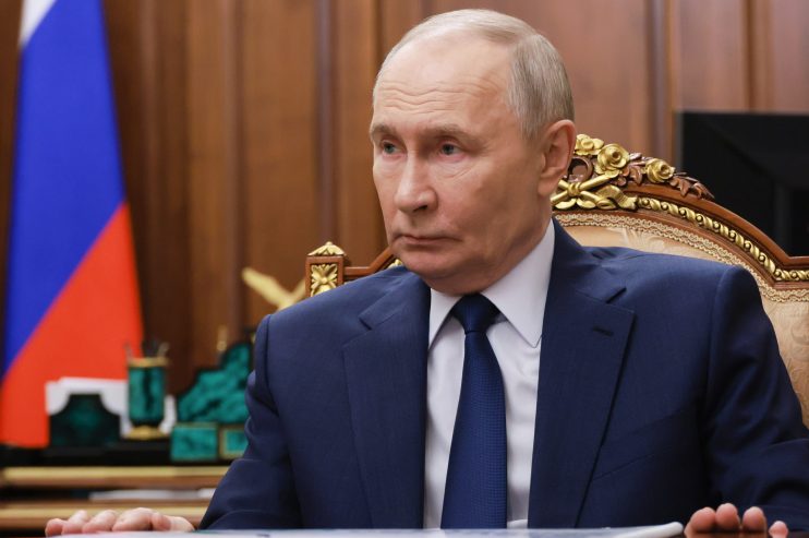 Vladimir Putin delivering a speech at an official event, addressing international relations and economic policies.