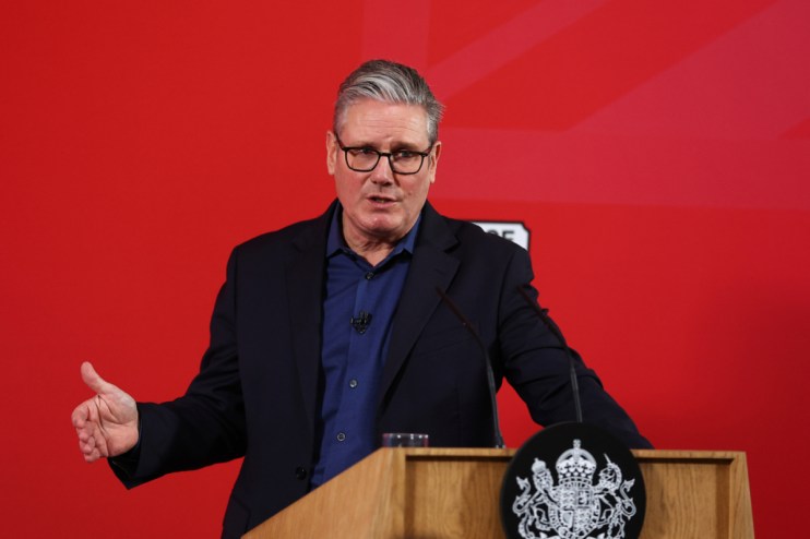 Prime Minister Keir Starmer addressing media at a public event, wearing a dark suit and tie, gesturing confidently