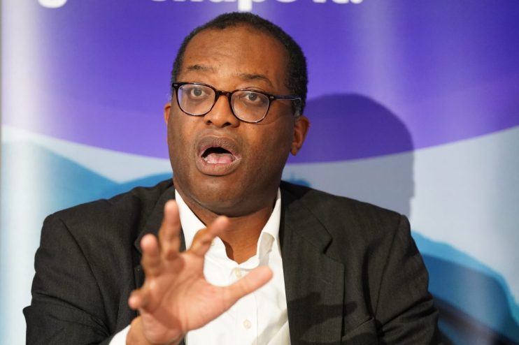 Kwasi Kwarteng speaking at a press conference, addressing economic policies, wearing a suit and tie, with a serious expres...