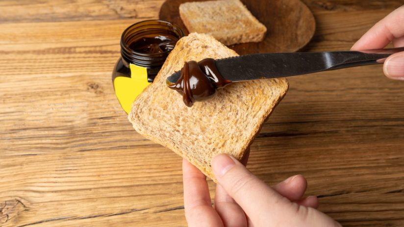 Marmite jar on a breakfast table with fresh bread and butter, highlighting its distinctive branding and popular breakfast ...