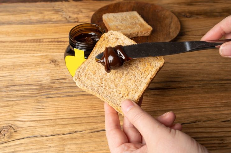 Marmite jar on a breakfast table with fresh bread and butter, highlighting its distinctive branding and popular breakfast ...
