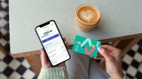 Woman using Zopa Bank credit card and smartphone app, demonstrating digital banking on-the-go features.